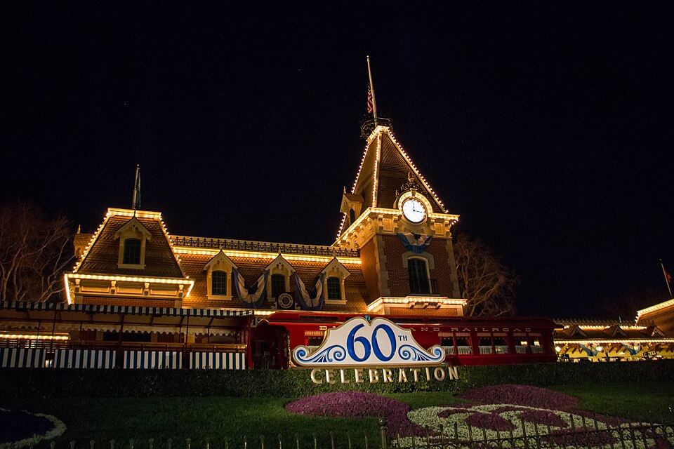 Disneyland Railroad’s Main Street station illuminated at night in a 2016 photograph by HarshLight.